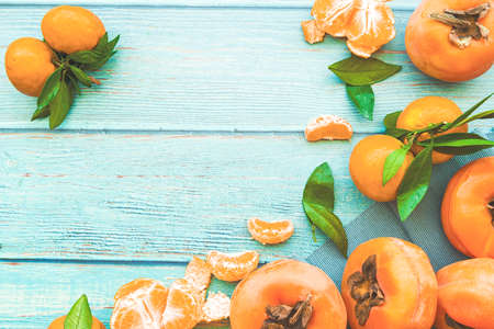 persimmons and tangerines on blue wooden background top viewの写真素材