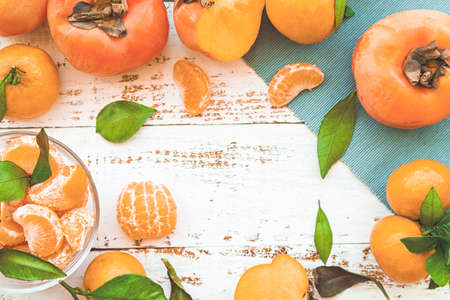 persimmons and tangerines on white wooden table top viewの写真素材