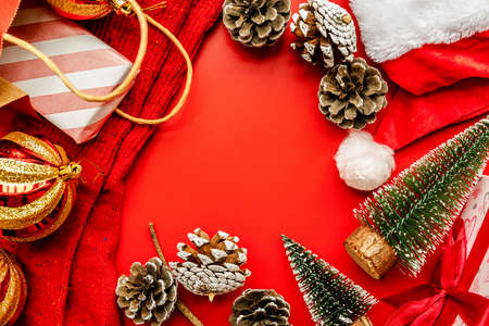 christmas concept. Christmas socks, gifts,pine cones, santa's hat and fir trees on red background top view flat layの写真素材