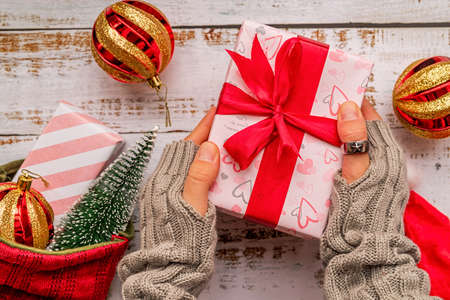 Christmas present with female hands on white rustic background