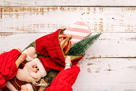 woman hands holding Christmas stocking with gifts on white wooden backgroundの写真素材