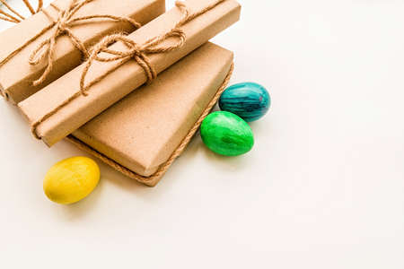 Easter gifts in craft paper, eggs and pussy-willow branches on white background flat lay top viewの写真素材