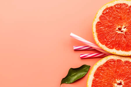 two grapefruit slices and drinking straws on pink background with copy space. Minimal conceptの写真素材