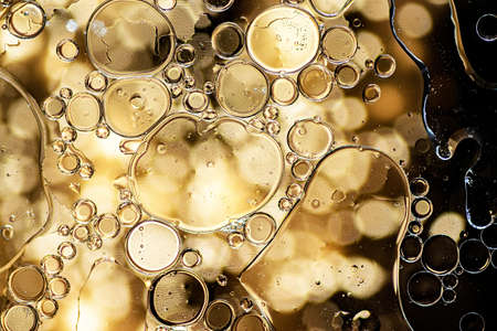 Abstract background. Black and yellow oil bubbles on waterの写真素材