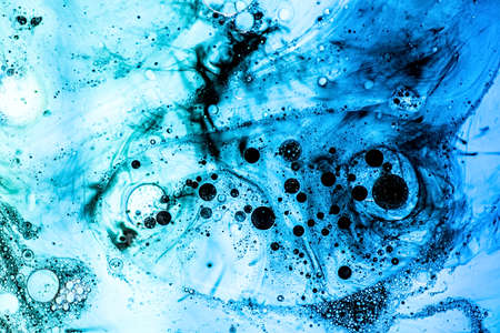 Bright blue bubbles with black ink on water surface in abstract background