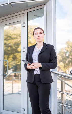 Business woman concept. Beautiful caucasian business standing outdoors holding her digital tablet....