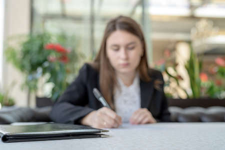 Blurred business woman having a cup of coffee on lunch break at the restaurant. Young professional businesswoman sitting at table at cafe with copy spaceの写真素材
