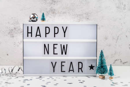 Christmas and New Year concept. White letter lightbox with Happy New Year words surrounded with christmas decorationsの写真素材