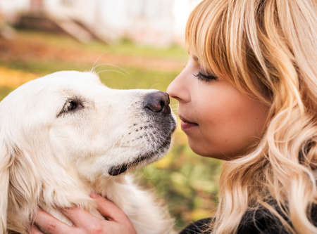 Pet care concept. Happy blond woman hugging her retriever dog in the park