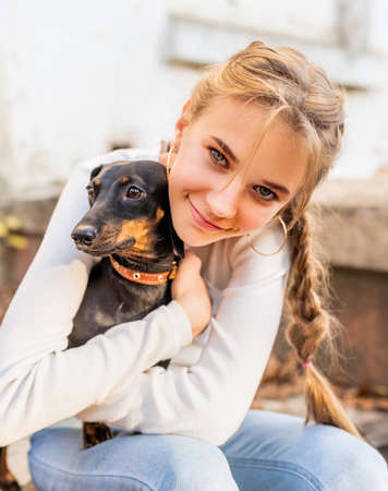 Pet care concept. Young woman hugging her dachshund dog outdoors. Focus on woman faceの写真素材