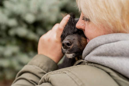 Pet care concept. Blond caucasian woman playing with her dog outdoorsの写真素材