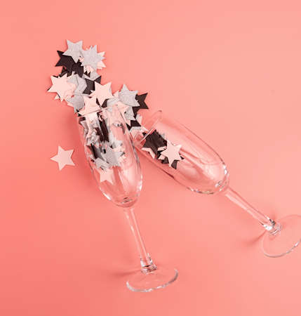 holidays concept. star shaped confetti pouring out of the glass on pink background flat lay top view