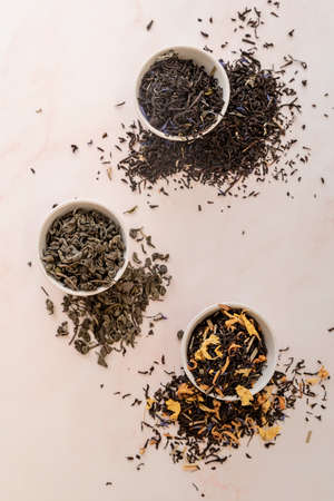 Top view of three white cups filled with dry tea leaves flat lay