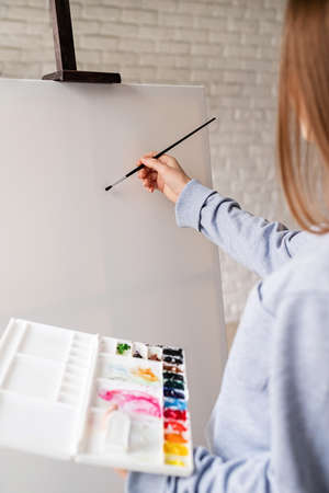 Woman hand holding a paintbrush againt the blank canvas with copy spaceの写真素材