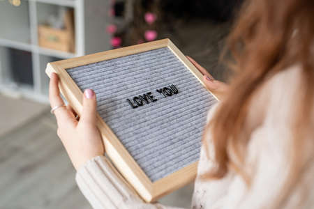 Valentines Day concept. Young beautiful woman holding felt letter board with the words Love Youの写真素材