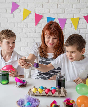 Easter fun and joy. Happy family coloring easter eggs at homeの写真素材