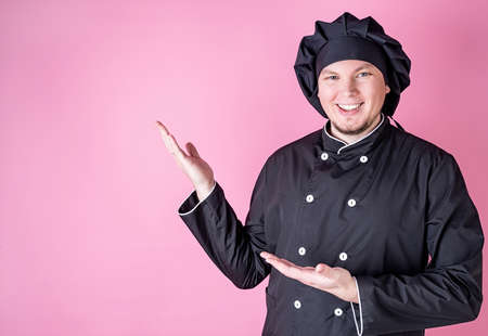 Young smiling male chef isolated on pink background with copy spaceの写真素材