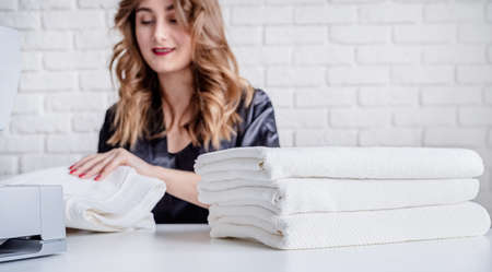 Beautiful housewife sewing towels at home using a sewing machine. Selective focusの写真素材