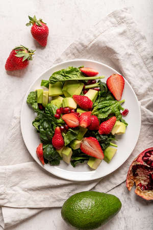 Healthy dieting. Fresh salad with strawberries, avocado and spinach top view flat lay on white...