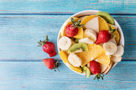 Healthy dieting. Fresh fruit salad on blue wooden background top view copy spaceの写真素材