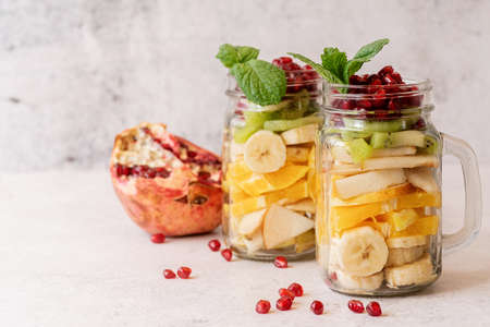 Healthy dieting. Fresh fruit salad with pomegranate in mason jars front view with copy spaceの写真素材