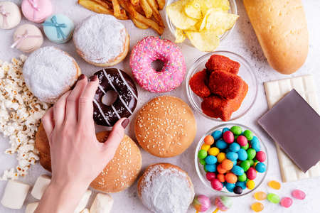 Fast food concept. Unhealthy food. Unhealthy food and fast food with donuts, chocolate, burgers and sweets top viewの写真素材