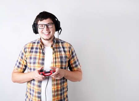 Stay home. Smiling young man playing video games holding a joystick isolated on gray background with...