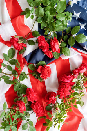 Independence Day USA concept. Memorial Day. Red roses over the USA flag top view flat lay with copy spaceの写真素材