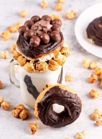 chocolate donut milkshake in a mason jar decorated with caramel popcorn, whipped cream and cocoa candiesの写真素材