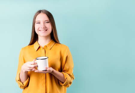 Young caucasian woman wearing a drinking coffee or tea over blue background with copy space