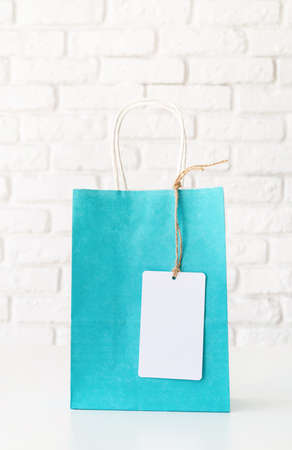 blue shopping bag with blank white tag on white tableの写真素材