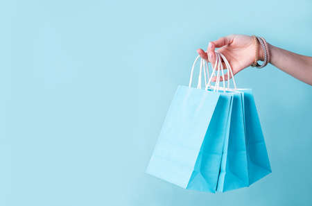woman hand carrying a bunch of blue shopping bags over blue background with copy spaceの写真素材