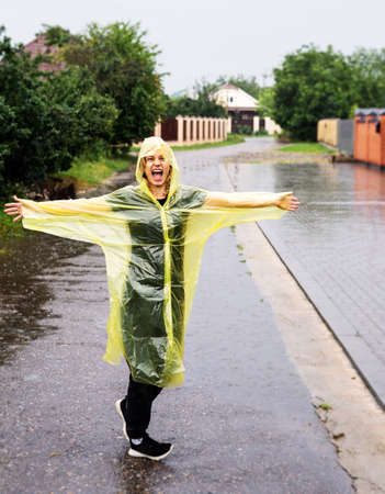 Happy caucasian woman in a yellow raincoat enjoying the rainの写真素材