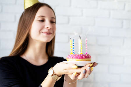 Teenager birthday girl blowing candles on the donutの写真素材