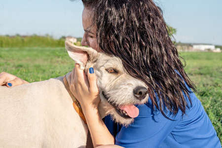Pet care. Pet adoption. Young woman playing and hugging her dog in the park