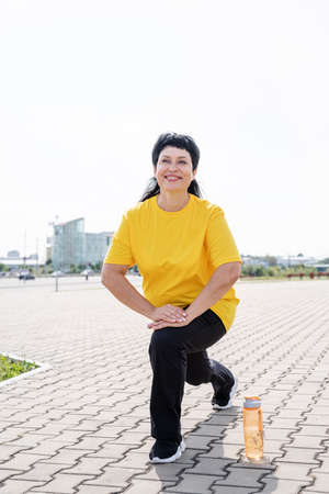 Sport and fitness. Senior sport. Active seniors. Smiling senior woman stretching outdoors in the parkの写真素材