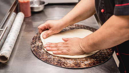 female baker hands making dough for pizzaの写真素材