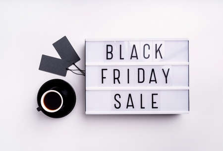 Black Friday shopping sale concept. Black Friday Sale words on lightbox with cup of coffee and black price tags top view flat lay on white backgroundの写真素材