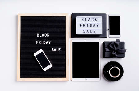 Black friday, seasonal sale concept. Text black friday sale on black letter board with cup of coffee, smarfphone, price tags on white backgroundの写真素材
