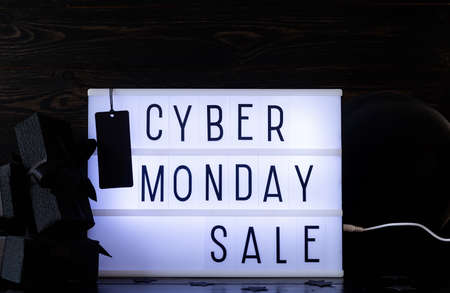 Cyber Monday shopping sale concept. Cyber Monday Sale words on lightbox with black price tag and gifts front view on dark backgroundの写真素材