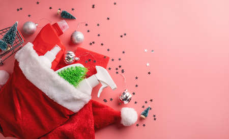 Christmas cleaning. Christmas shopping. Cleaning tools and Christmas decorations in santa hat top view flat lay on pink background with copy spaceの写真素材