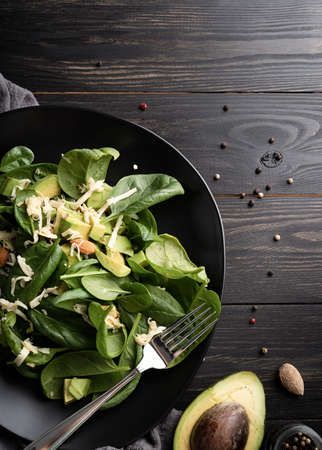Top view of fresh summer avocado and spinach salad bowls, flat lay copy space on dark backgroundの写真素材