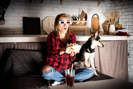 Young woman in 3D glasses watching movies at home at night at christmas