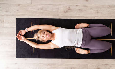 Healthy lifestyle. Young attractive woman practicing yoga, wearing sportswear, white shirt and...