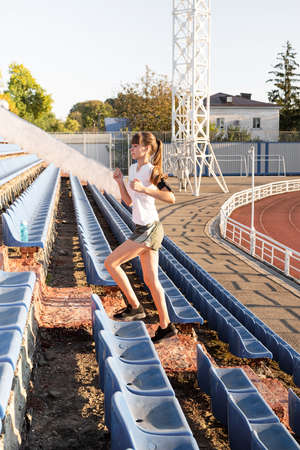 Sports and fitness. Teenager girl getting ready to run at stadium trackの写真素材