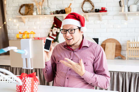 Christmas baking concept. Man in santa hat whipping egg whites with the electric mixer in the kitchenの写真素材