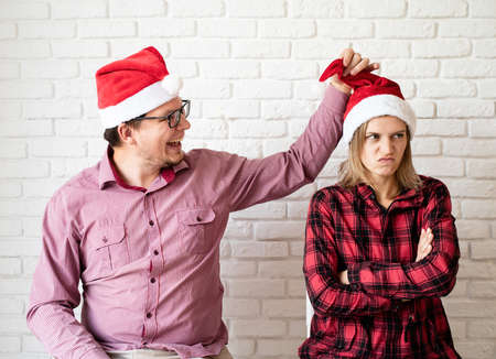 Christmas online greetings. Happy young couple in santa hats greeting their friends in a video call on laptop sitting at the kitchenの写真素材