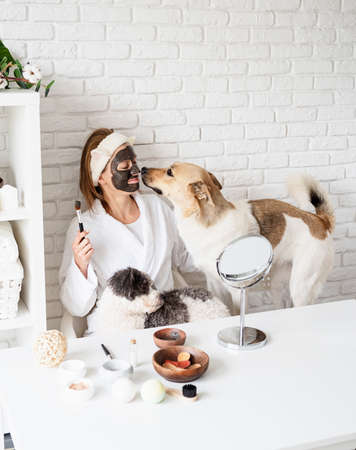 Pet care. Funny smiling young woman in yellow plaid sitting with her dogs reading a bookの写真素材