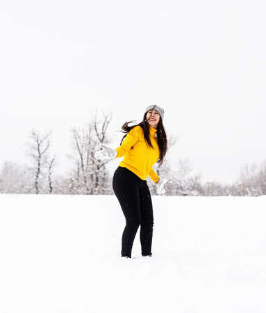 Outdoor concept. Young brunette woman playing with snow in parkの写真素材