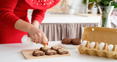 Valentines Day. Woman in red dress making valentine cookies at the kitchenの写真素材